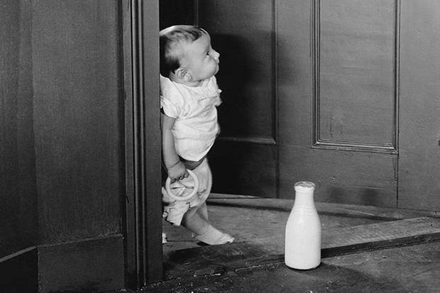Baby opens door to a bottle of milk delivered.