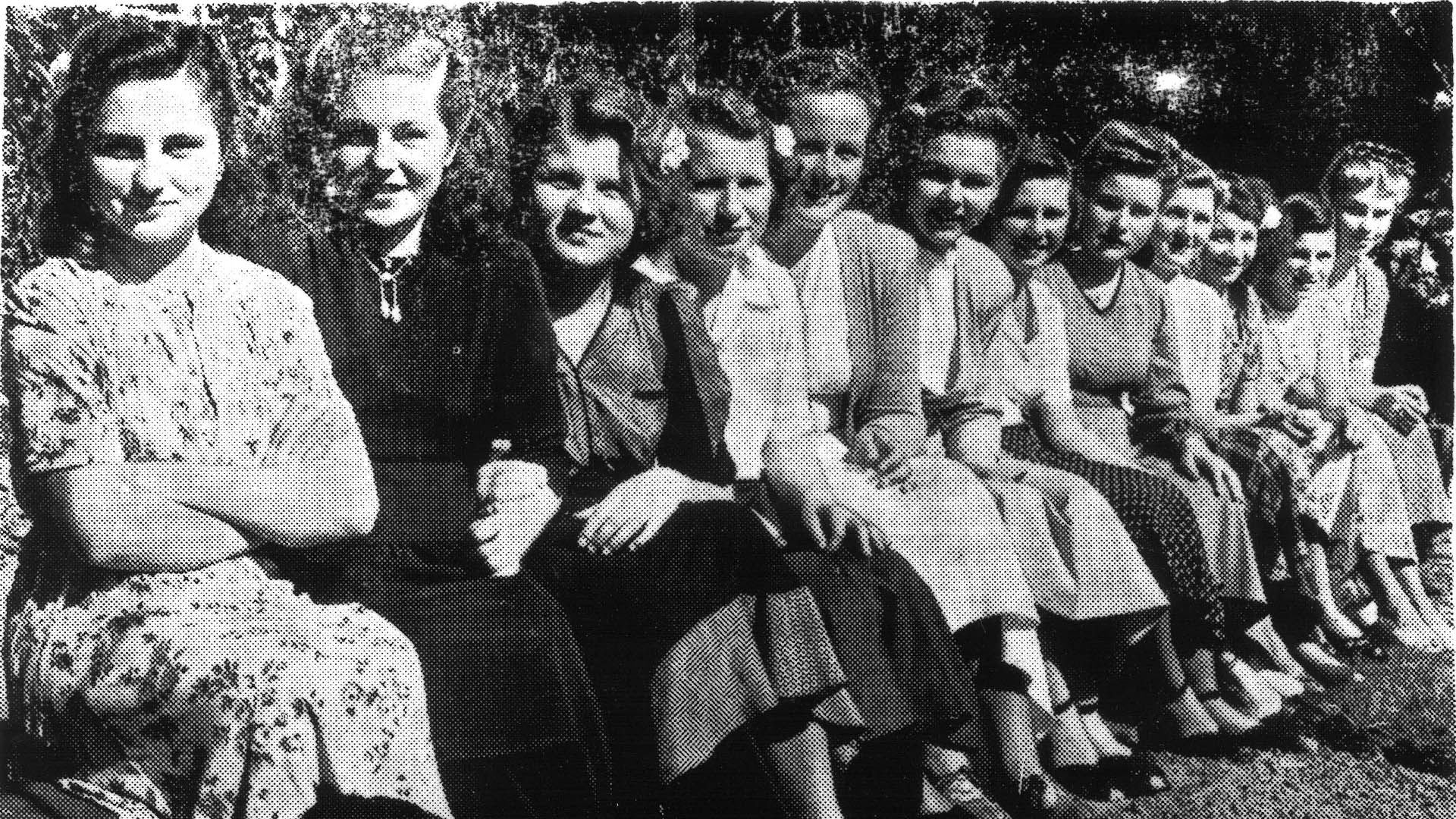 A 1950s newspaper photo of several woman, sitting side by side outside